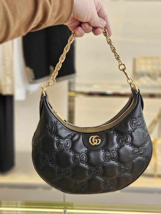 mulher bonita segurando uma bolsa com alça de corrente dourada