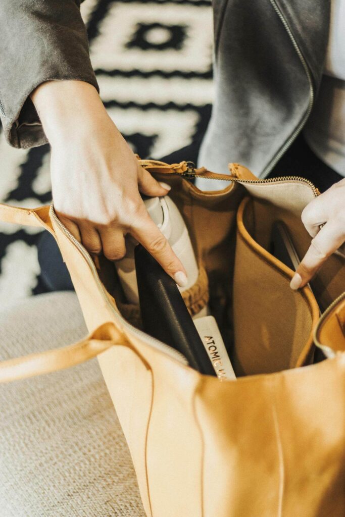 Mulher organizando sua bolsa de trabalho colocando itens dentro da bolsa