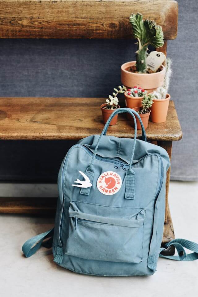 mochila no chão encostada aos pés de um bando de madeira